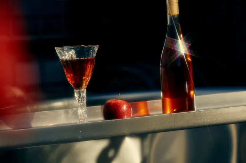 Wine bottle and glasses on a sunlit cellar surface