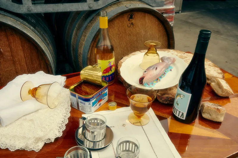 Wine, glasses and food on a table in front of barrels